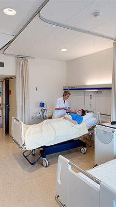 Una enfermera atiende a su paciente en una habitación del UMCG, iluminada con soluciones de ahorro de energía de Philips Lighting