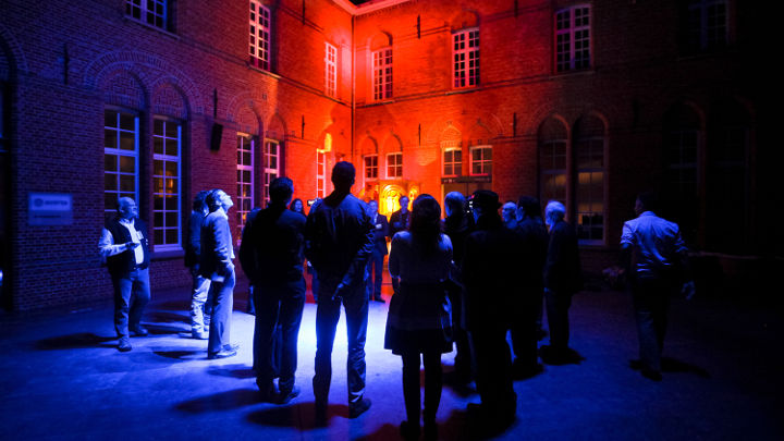 Un gran grupo de personas debate en el exterior de un edificio agradablemente iluminado en Turnhout (Bélgica) en un taller organizado por Philips